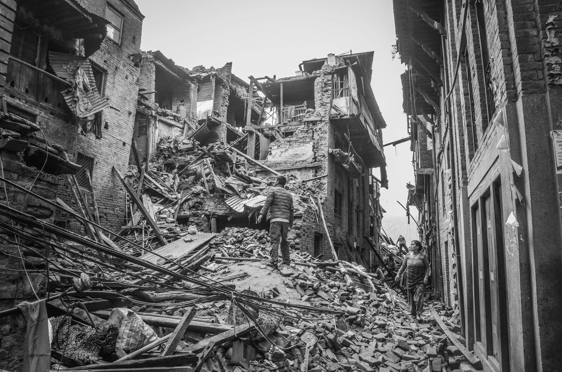 people looking at wrecked buildings